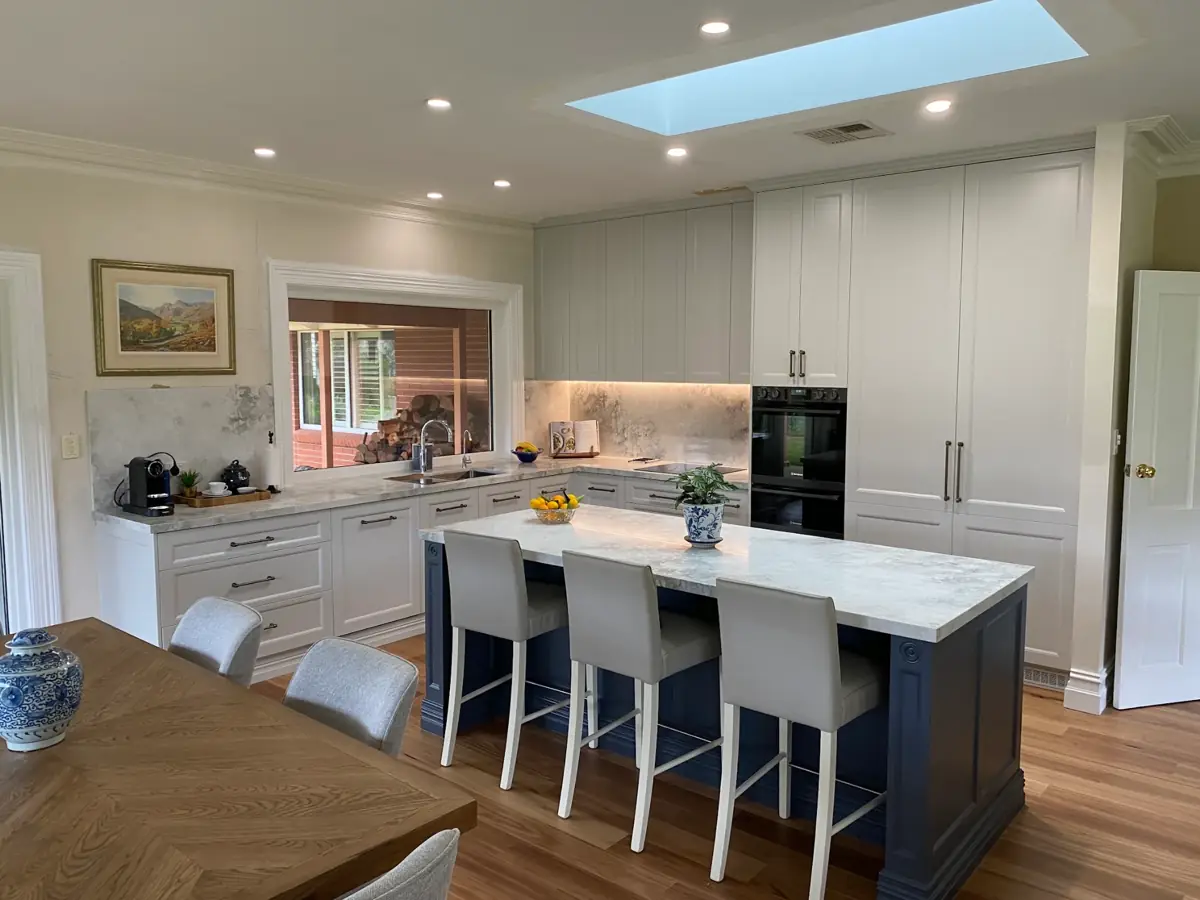 A classic shaker kitchen with a navy island bench, stone benchtops and skylight above