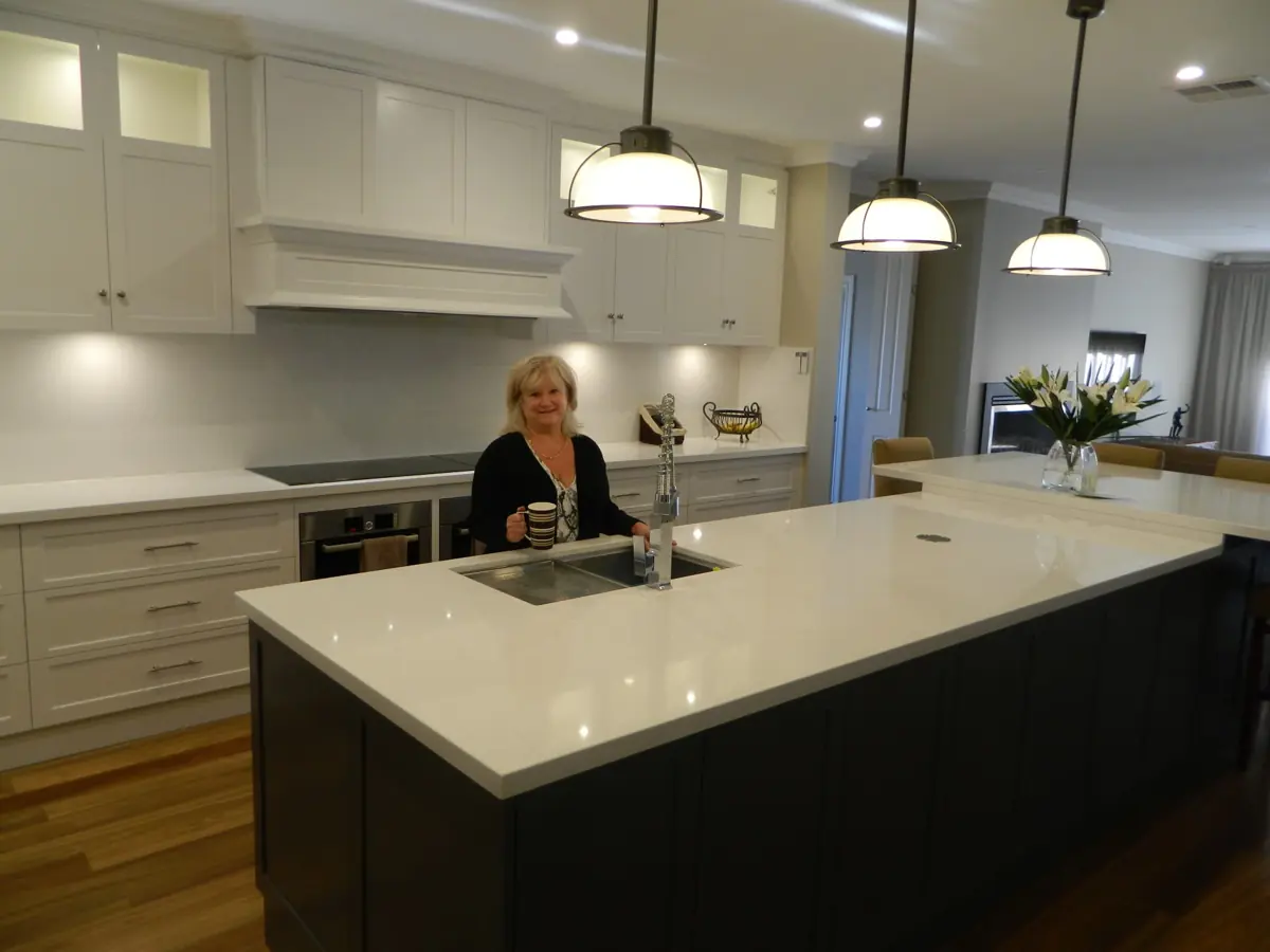 A client in a completed Haute Kitchens shaker-style kitchen with a large stone island bench